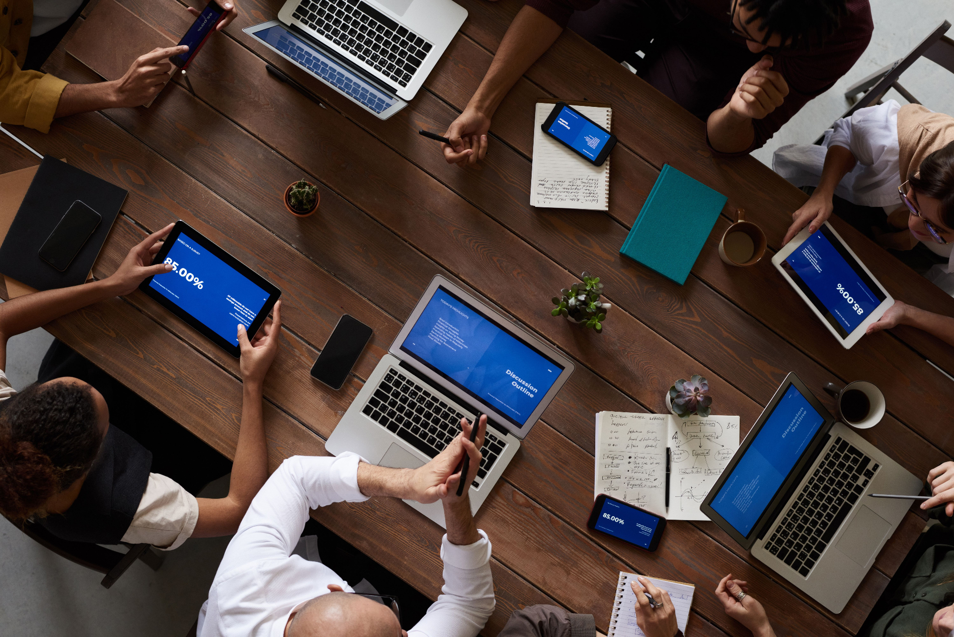 Reunião ao redor de mesa com laptops e tablets